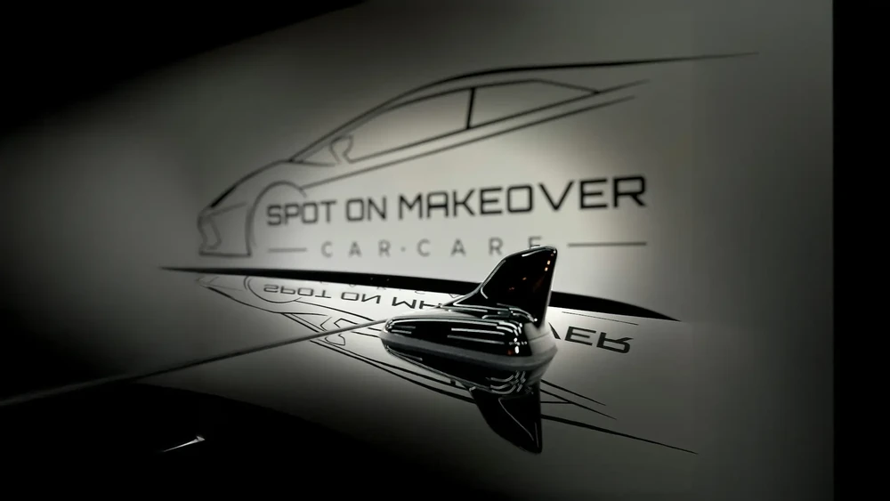Intérieur d'atelier automobile avec logo "SPOT ON MAKEOVER CAR CARE" projeté sur mur blanc