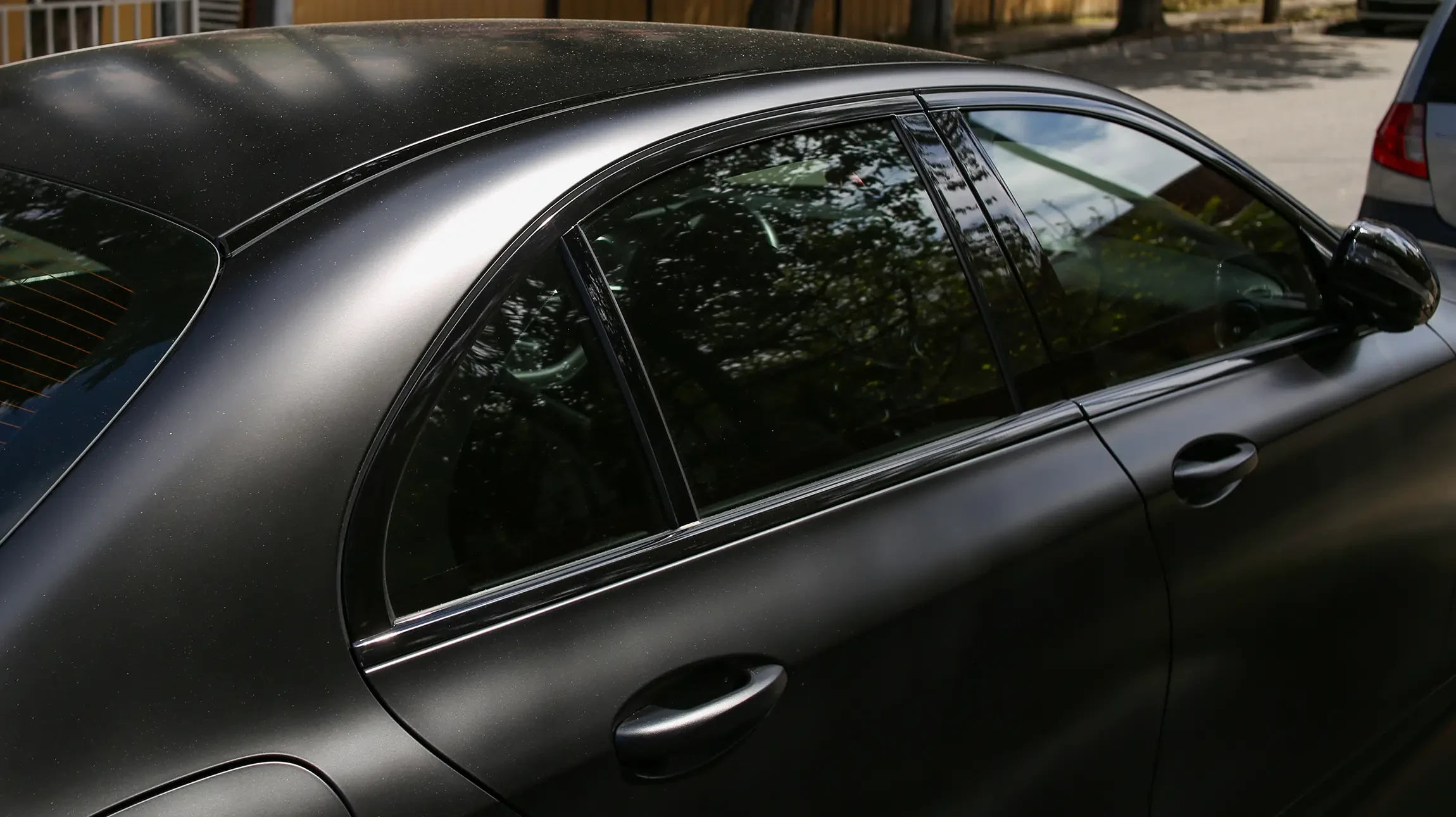 Scène extérieure avec voiture de sport noire sur surface asphaltée sous ciel nuageux