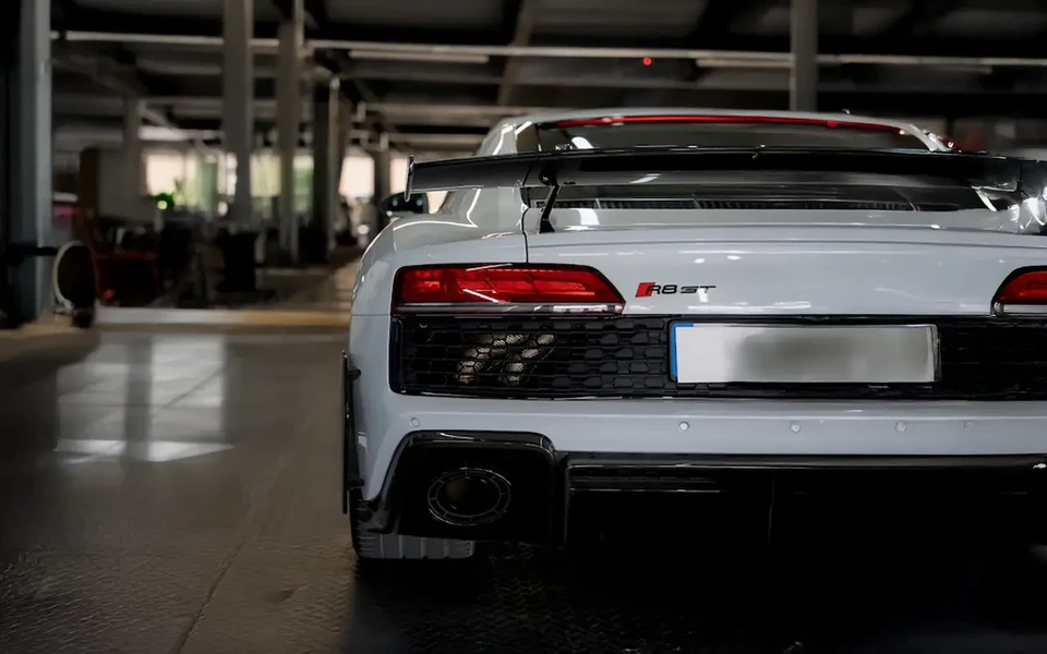 Atelier automobile intérieur, technicien en gants noirs utilisant une polisseuse électrique sur carrosserie blanche de véhicule